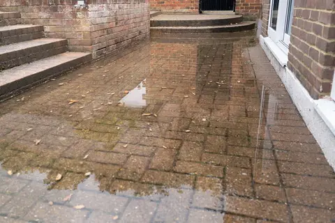 Wasser steht auf einer Terrasse vor einer Hauswand