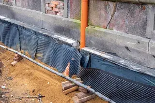 Freigelegte Kellerwand mit Noppenbahn und Drainagerohr