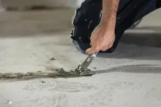 Handwerker schließt Risse in einem Kellerboden